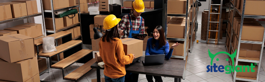 three warehouse staff are discussing in a room with boxes